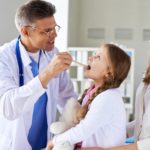 parent and adult child sitting with a doctor, discussing healthcare at childcare hospital